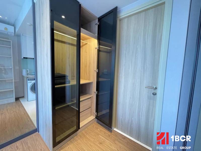 A wardrobe with open doors in a 2-room apartment, next to the kitchen area.