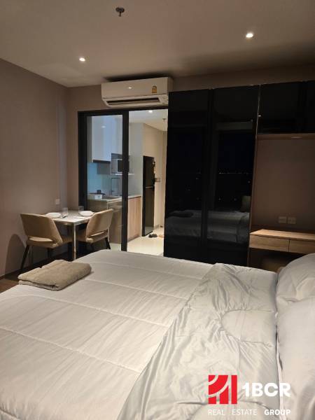 Interior of a 1-room apartment with a bed, dining table, and kitchen.