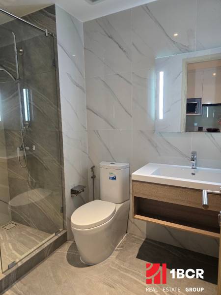 Bathroom in a studio apartment with an open shower and a mirror above the sink.