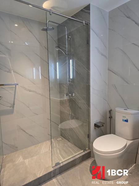 Bathroom in a studio apartment with a glass shower enclosure and a toilet.