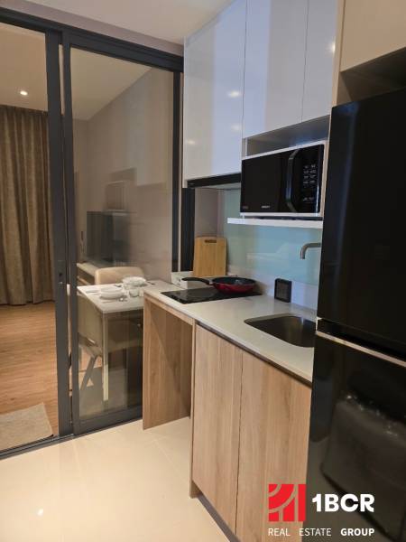 A kitchen in a studio apartment with a ceramic hob and a microwave oven.