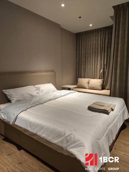 Bedroom in a one-room apartment with a double bed and a brown carpet.
