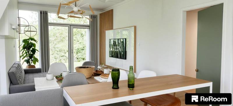 Dining table with drinks, TV on the wall, view into the garden, 3-room apartment.