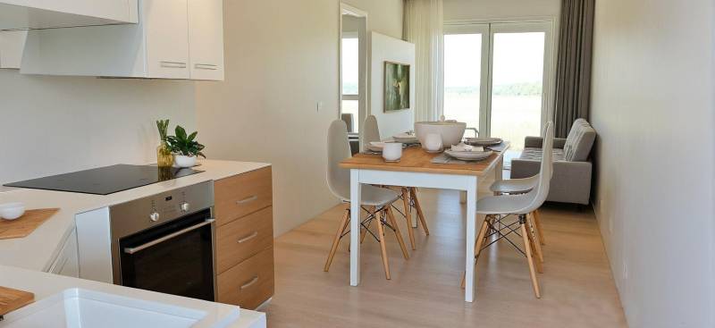 Dining table with chairs and a kitchen in a 3-room apartment with bright decor.
