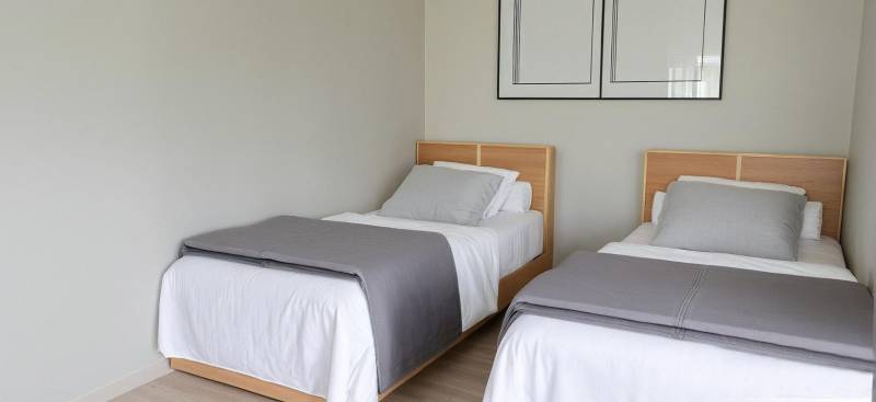 Two single beds with gray covers in a 3-room apartment.