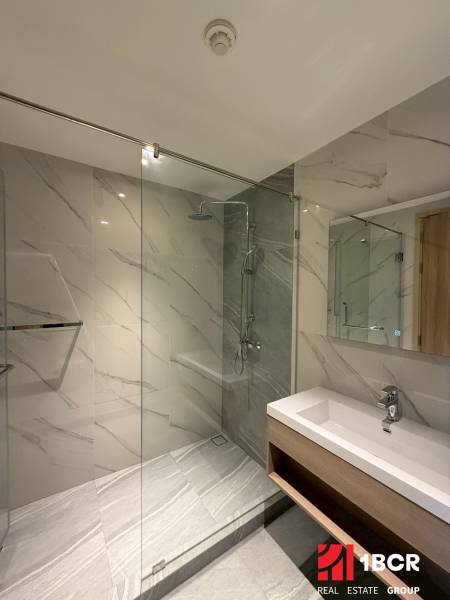 A bathroom in a 3-room apartment with a large shower and an elegant sink.