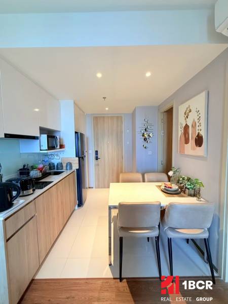 Kitchen and dining area in a 3-room apartment with wooden and white cabinets.