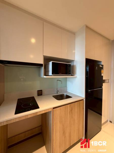 Compact kitchen unit with a cooktop and microwave in a studio apartment.