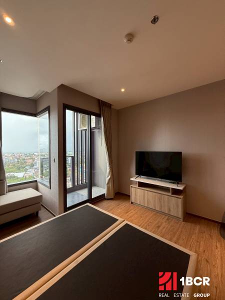 Living room in a studio apartment with a TV, sofa, and view.