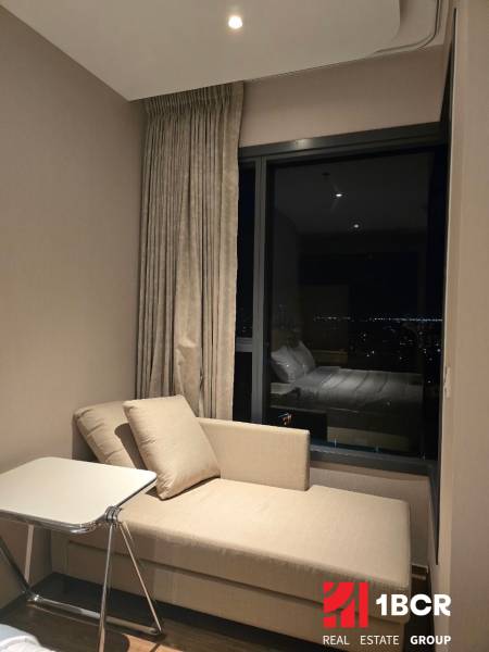 A sofa and a table in a studio apartment with a night view.