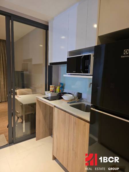 A kitchen in a studio apartment, equipped with appliances and cabinets.