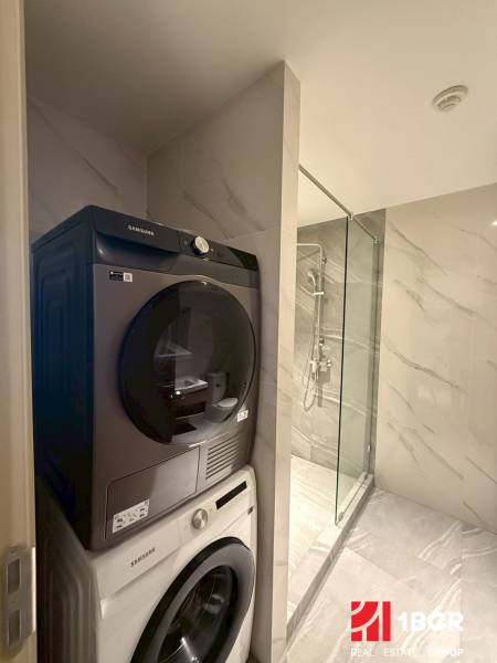 A bathroom in a 3-room apartment with a washing machine and dryer next to the shower.
