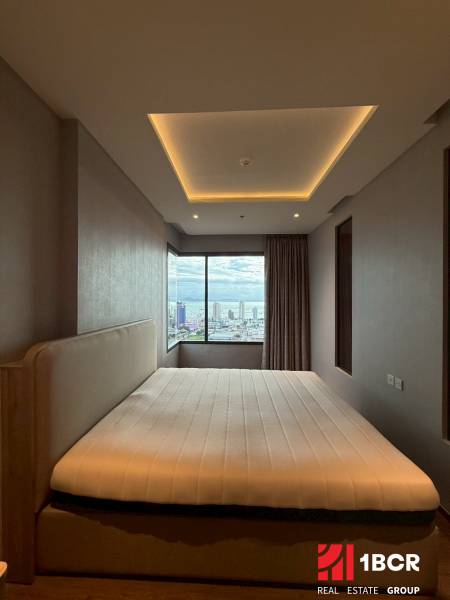 A bedroom in a three-room apartment with a large window and a view of the city.