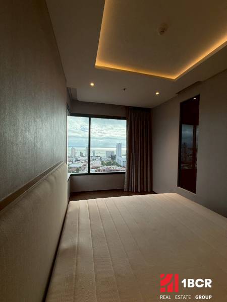 A bedroom in a 3-room apartment with a view of the city through a large window.