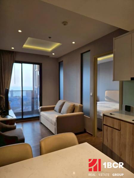 Living room in a 3-room apartment with a sofa, view, and kitchen counter.