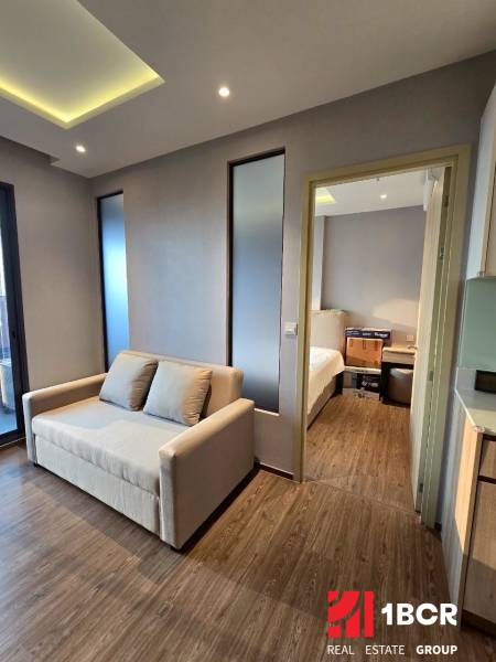 Bright living room in a three-room apartment with a sofa and wooden floor.