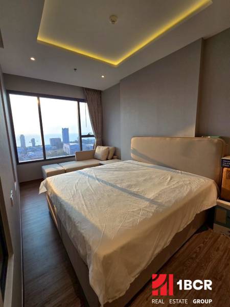 3-bedroom apartment with a bed and a view of the city and the sea.