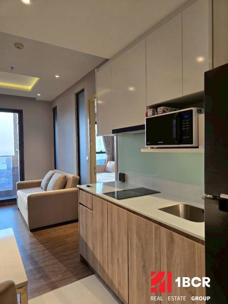 A kitchen in a 3-room apartment with a sofa, a hob, and a microwave.