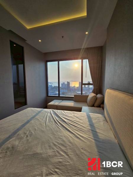 A bedroom in a 3-room apartment with a view of the sunset over the city.
