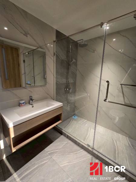 A bathroom in a 3-room apartment with a large mirror and a shower corner with a glass partition.
