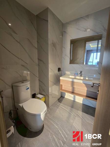 A bathroom with marble tiles and a toilet in a 3-room apartment.