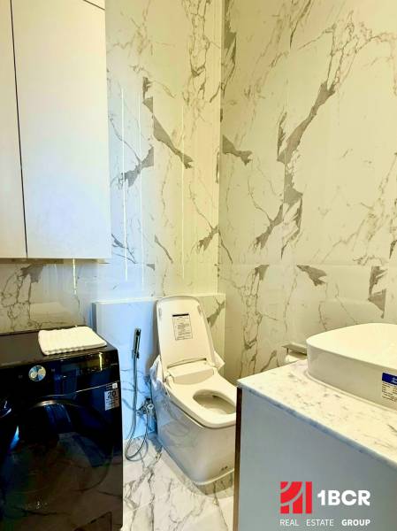 A bathroom in a 4-room apartment with a toilet, washing machine, and marble walls.
