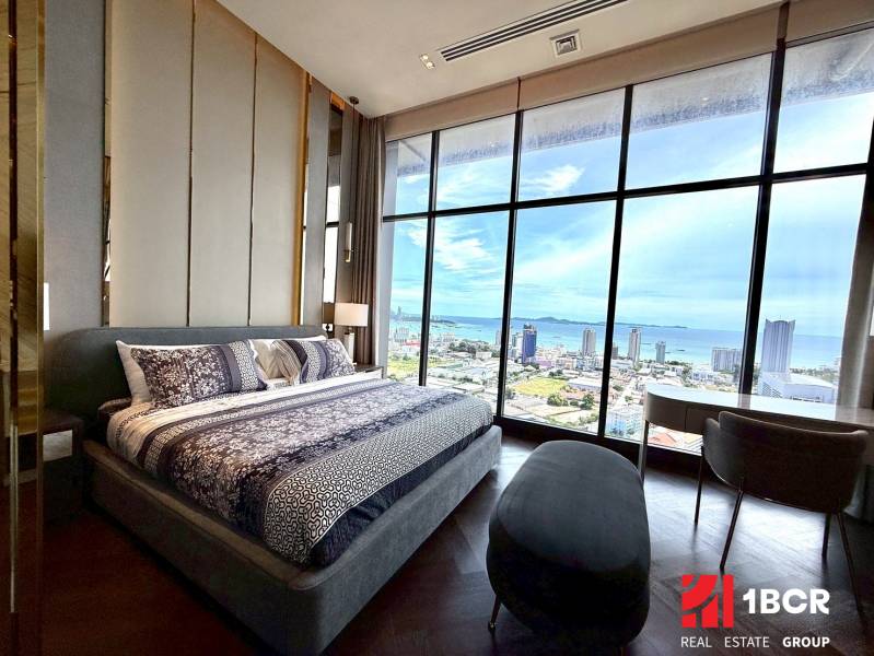 The bedroom in the 4-room apartment with a large window offers a view of the city and the coast.