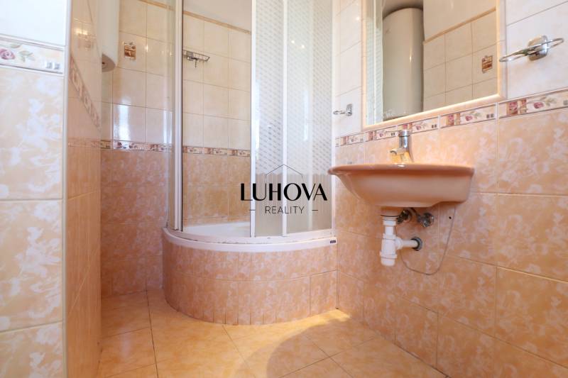 A bathroom with tiles and a shower in a 2-room apartment.