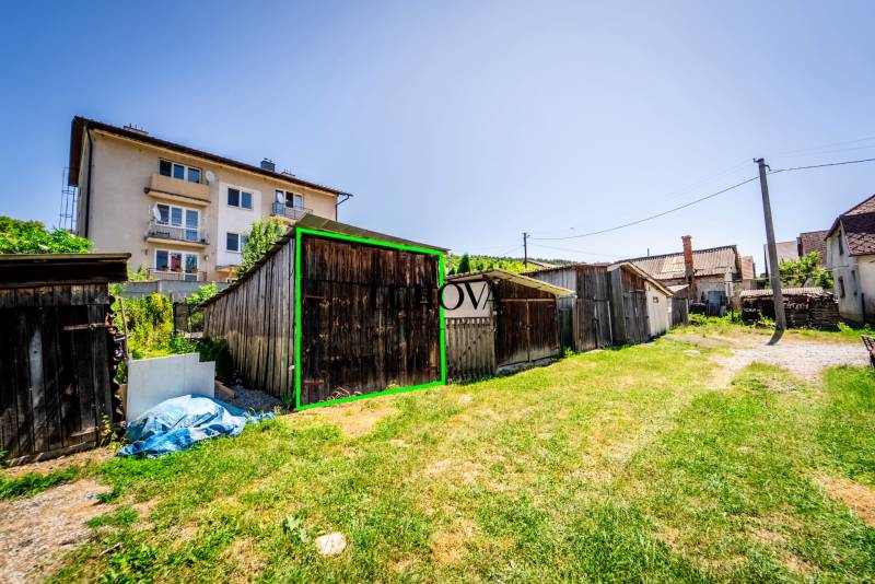 A yard with wooden cottages and an apartment building in Púchov.