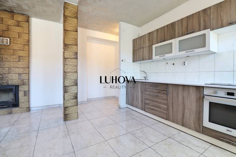 A kitchen in a 2-room apartment with wooden paneling and tiled flooring.