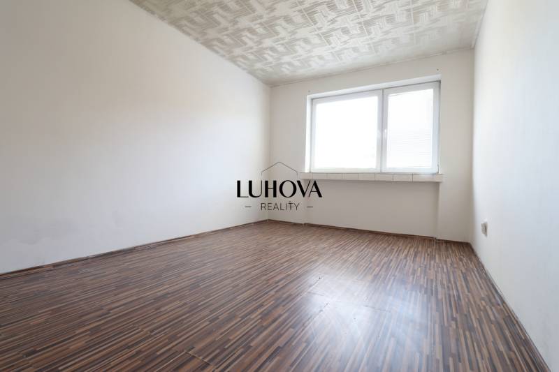 An empty room with a patterned floor and a large window in a 2-room apartment.