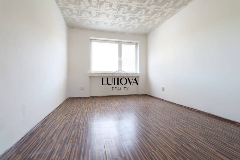 An empty room with a wooden floor and a white ceiling in a 2-room apartment.