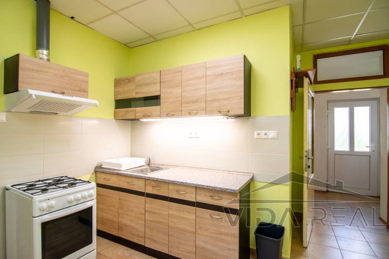A kitchen with a gas stove, wooden cabinets, and a light green wall in a 2-room apartment.