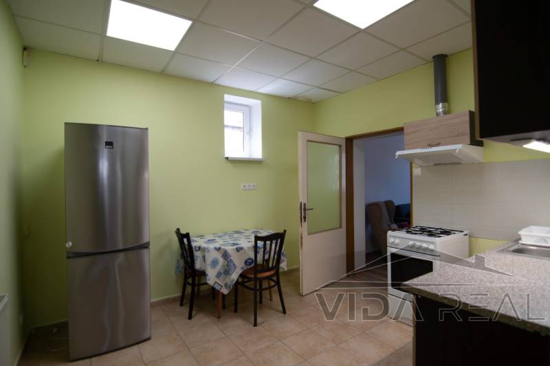 A kitchen with a table, refrigerator, and stove in a 2-room apartment, light green walls.