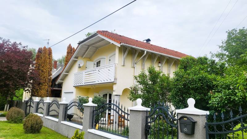 A family house in Dunaszige with a red roof, a balcony, and a well-maintained garden.