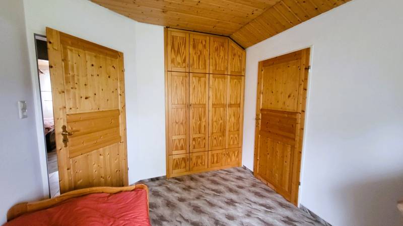 A room in a family house with a built-in wooden wardrobe and doors.