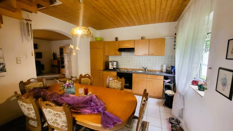 Dining room and kitchen in a family house with a wooden ceiling and decorative lighting.