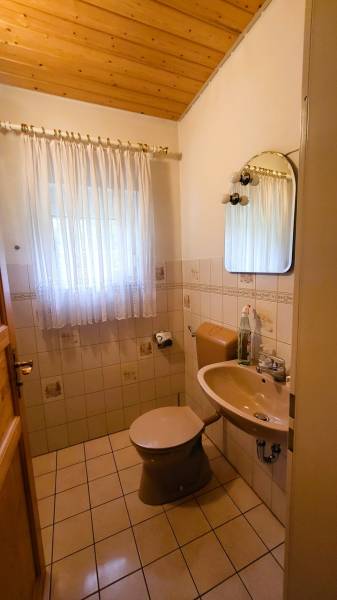 A bathroom in a family house with tiles, a curtain, and a mirror.