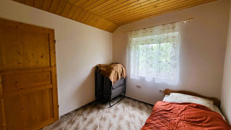 A room with a wooden ceiling and a bed in a family house.