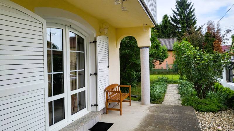 A family house in Dunaszigeţ with a terrace and a bench surrounded by a garden.