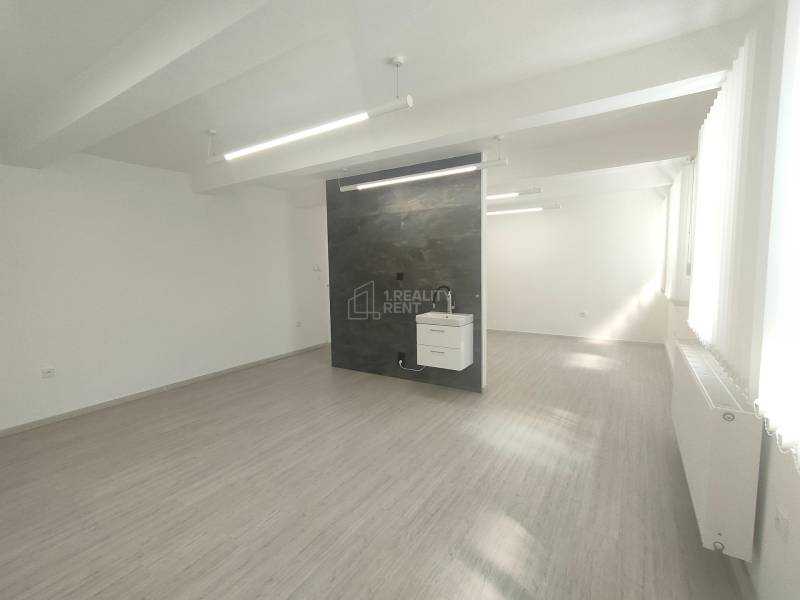 Commercial premises with a sink and a dark wall, equipped with lighting fixtures, underfloor heating.