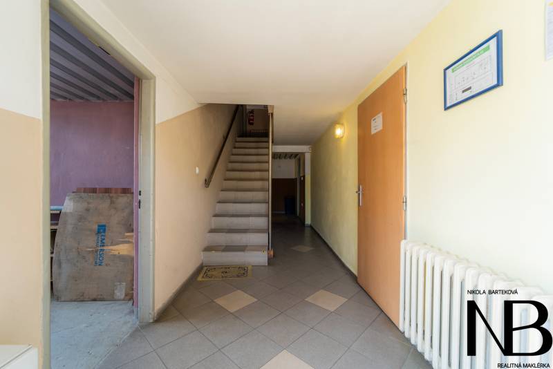 Entrance hallway with stairs, doors, and a radiator in the warehouse and hall areas.