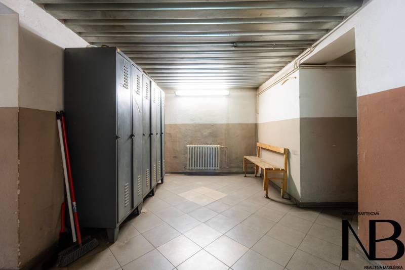 Warehouses and halls with metal lockers, a bench, and cleaning supplies in the corner.