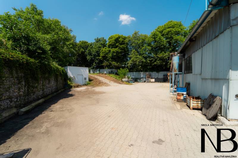Paved area at the warehouse hall on Kasárenská Street in Trenčín surrounded by greenery.