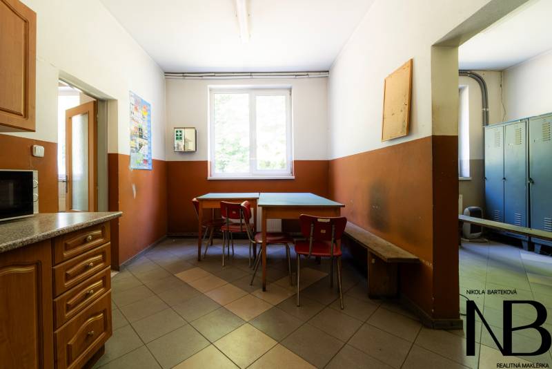 Manufacturing premises with a dining table, chairs, cabinets, and a microwave.