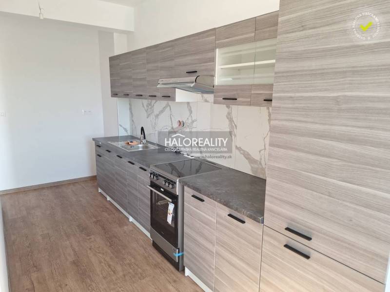 A kitchen in a 2-room apartment with wooden flooring and gray cabinets.