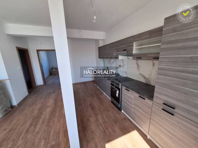 The kitchen of a 2-room apartment with wooden floors and gray cabinets.