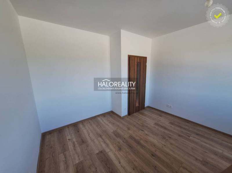 A room with a wooden floor and white walls, part of a 2-room apartment.