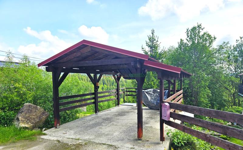 A shelter with a wooden structure by a family house in Donovaly, surrounded by greenery.
