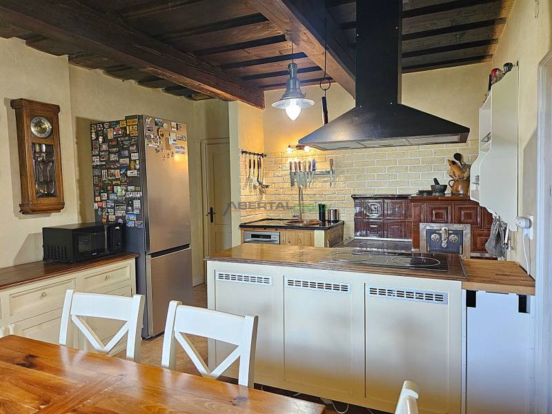 A kitchen in a family house with a wooden ceiling, a stove, and a solid table.